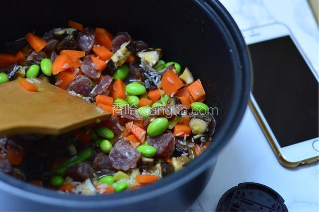 在饭煲中倒入炒好的食材搅均匀。