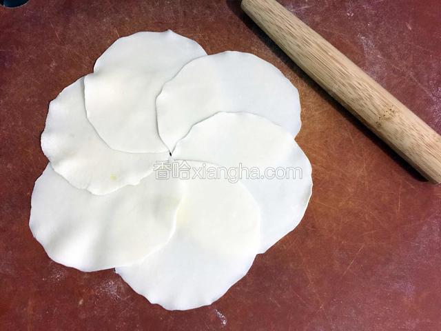 取出面团再揉揉，搓成长条，再切成大小相同的小面团，压平，用擀面杖擀成中间厚边边薄的面皮，像饺子皮一样的。