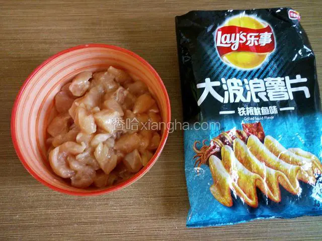 腌好的鸡肉丁和压碎的薯片，薯片袋子开口处剪开。
