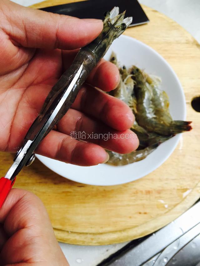 剪去虾须，并且用剪刀从虾的尾部剪开，剔除虾线