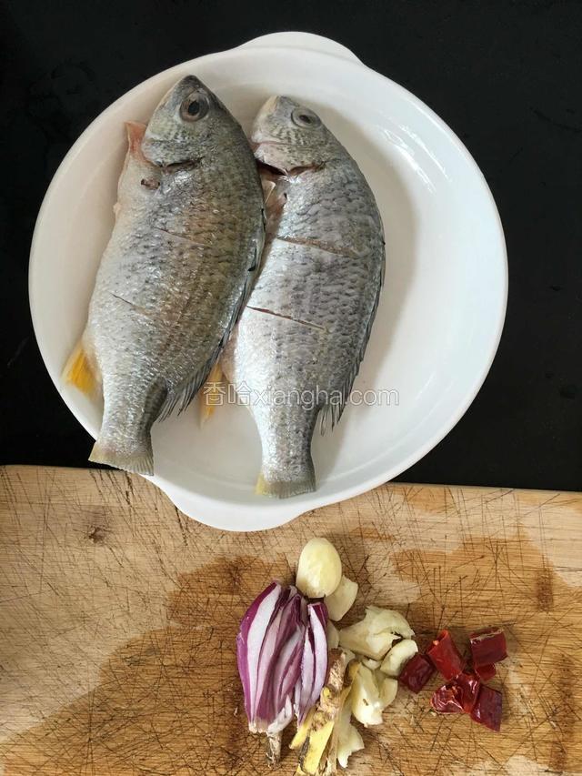 黑鲷鱼刮鱼鳞，清理内脏，冲洗干净。洋葱生姜切丝，大蒜拍碎备用。