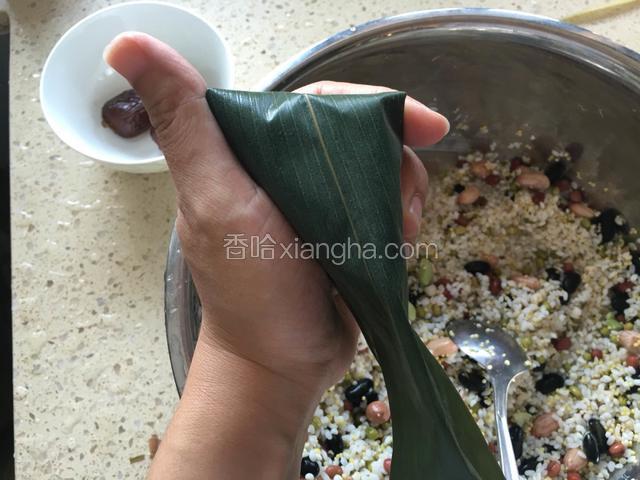 右手捋平粽子右侧，此时顶部成三角形。