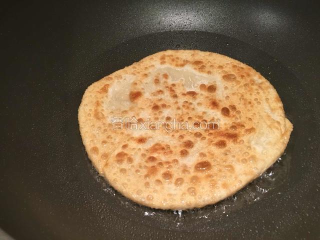 一边烙一边用铲子敲打饼的表面。看见饼表面又鼓起时，再翻面，继续烙。