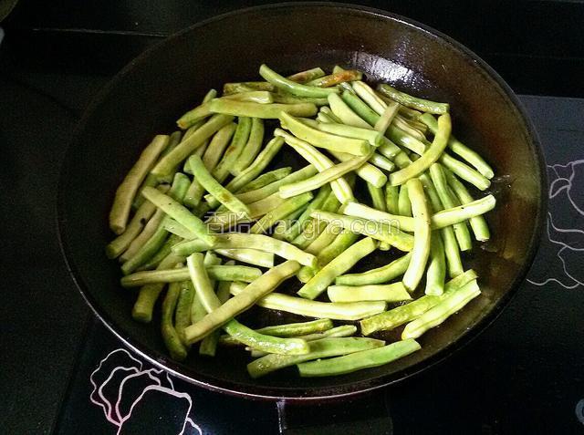 起炒锅放花生油，把豆角放进去煎。（干煸豆角通常都是用油炸，但在家里不想用太多油，我采用的是煎制。）