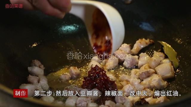 然后放入豆瓣酱、辣椒面，改中火，煸出红油，加料酒、放入葱姜蒜爆香。