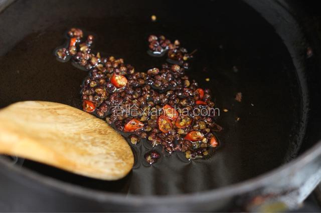 炸花生仁剩余的油加入一汤匙芝麻香油，加热后放入花椒和红辣椒丁煸香，呛锅后捞出花椒和红辣椒丁。