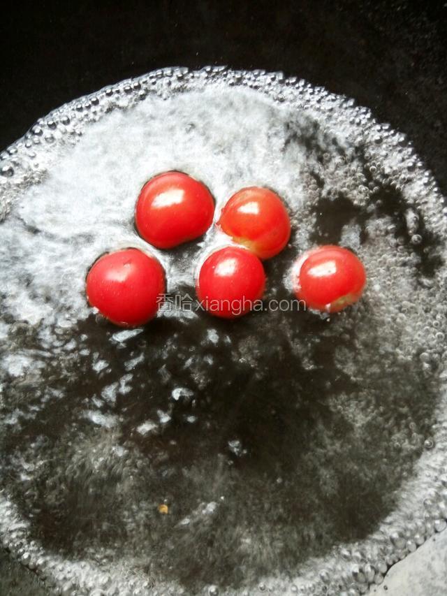 小番茄在锅里煮至皮裂开，捞出，剥掉皮备用