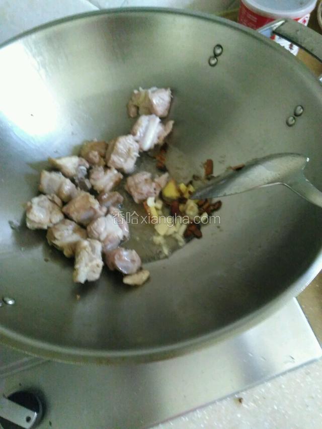 把排骨放入，翻炒片刻后，把姜和蒜还有八角桂皮一起放入，翻炒一分钟