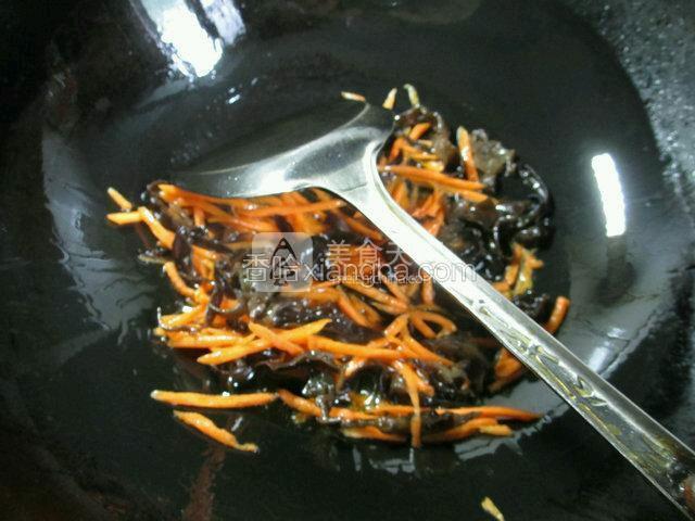  烧锅倒油烧热，下入胡萝卜丝和切好的黑木耳翻炒一下。