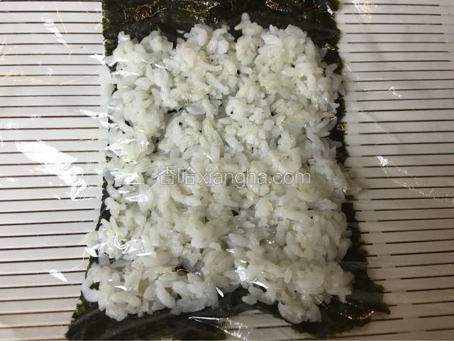 寿司卷上铺一片海苔，然后均匀地铺一层米饭，然后上面铺一层保鲜膜！然后翻过来，这样海苔就在上面，保鲜膜在下面！