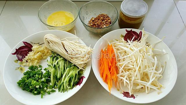 准备食材:黄瓜和胡萝卜切丝，切葱花和蒜末，花生用油炸出去皮擀碎，鸡蛋打散备用。