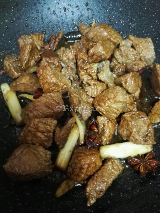 锅内热油，牛肉块用中火翻炒一分钟，在放入干辣椒，花椒，葱段，生姜，料酒，桂皮和八角翻炒至出香味，加入少许老抽上色