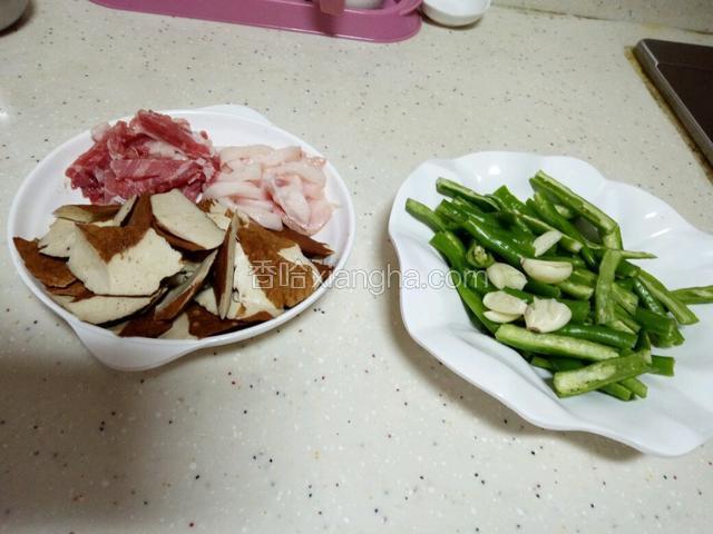 杭椒平剖一分为二，然后切段。猪肉切丝，茶干切斜片，备好蒜蓉