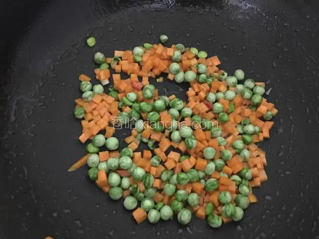 锅入油烧热，放入胡萝卜丁与豌豆翻炒均匀