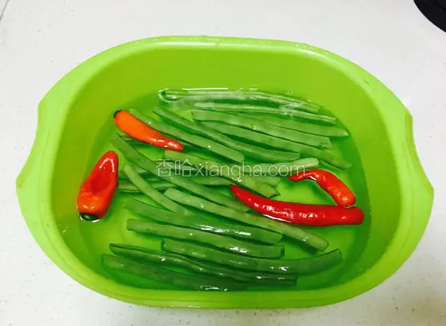 先把四季豆摘去两边的茎，放在清水中加盐浸泡30分钟。去除农药残留。