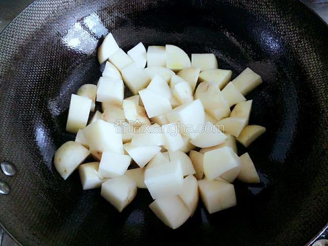 慢慢倒入控水的土豆块，以防烫伤，开中火，翻炒均匀