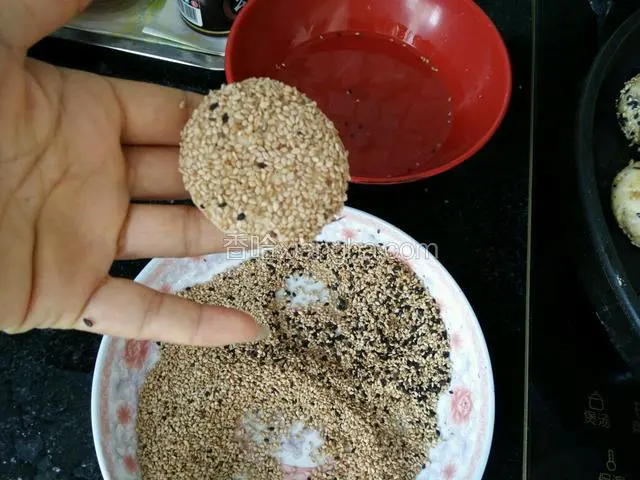 然后准备一碗水和适量的干芝麻，拿住包好的饼丕放进水里，接着拿出沾芝麻