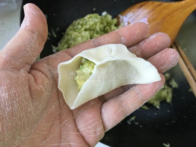 先捏紧饺子皮一边。