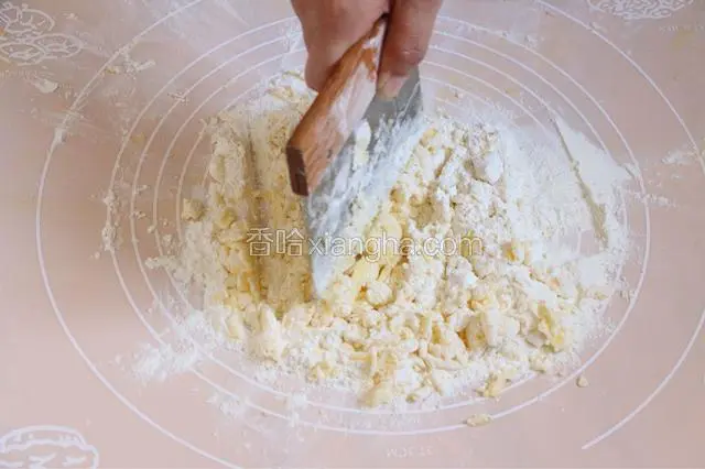 先制作酥皮部分。糖粉面粉混合过筛至操作台上。将冷藏黄油放在粉上，用刀切碎至无大颗粒。