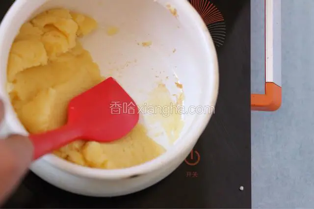 混合后继续加热并不断用刮刀翻拌。锅底上出现一层面团的薄膜(如图)，离火。把面团放到其他容器稍冷却。这里为能观察面团是否烫熟，换了一个塘瓷奶锅，不粘锅不容易分辨面团的状态。