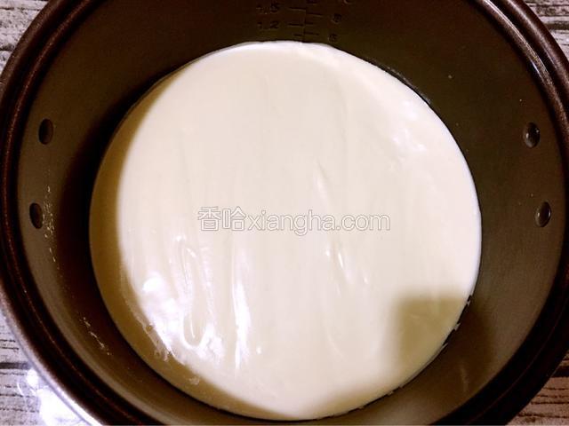 把蛋糕糊倒入电饭煲内胆中，拿刮刀抹平表面，用手端住电饭煲内胆用力震几下，把大气泡震掉。