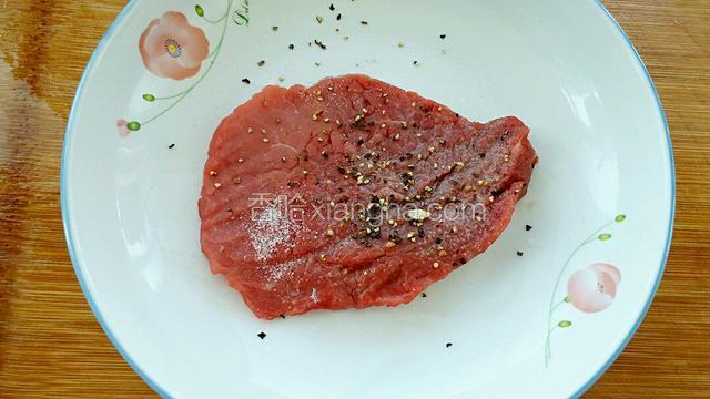 把牛里脊肉用肉锤敲松放入容器中，调入适量盐、柠檬汁和黑胡椒碎。