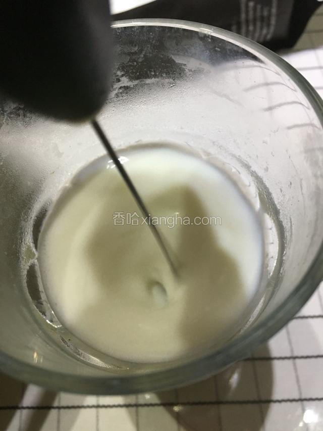 用电动打奶泡器斜入牛奶中。开始打起泡泡。