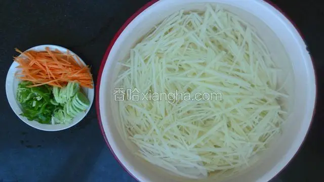土豆焯水过程中切好青辣椒丝、胡萝卜丝、葱花，焯好的土豆捞出后马上放入凉水盆中！