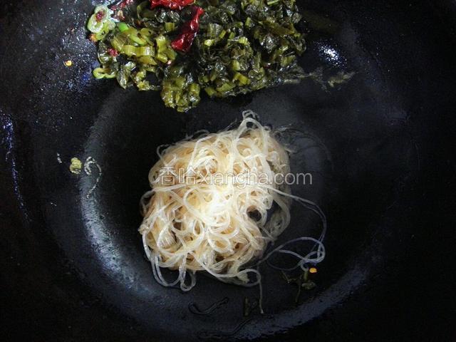 把酸菜拨到一边，放入粉丝，在粉丝上面放少量盐和生抽用筷子快速翻炒