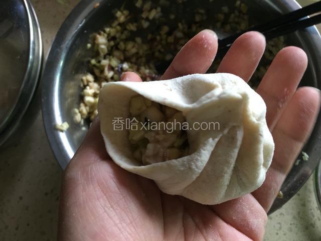 左右两手配合，右手拇指和食指捏住包子皮开始包，两手向相反的方向用力。