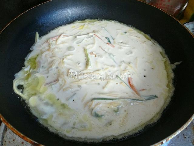 用勺子舀一勺南瓜丝糊倒入锅中！转下锅把糊均匀的摊开