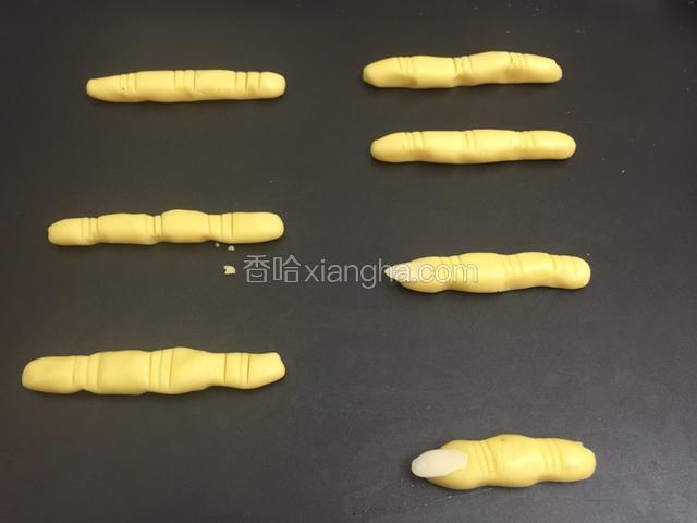 搓成手型状、稍微细长一点、在关节处用小刀背压个印子.把杏仁片粘点蛋清粘在手指上当指甲