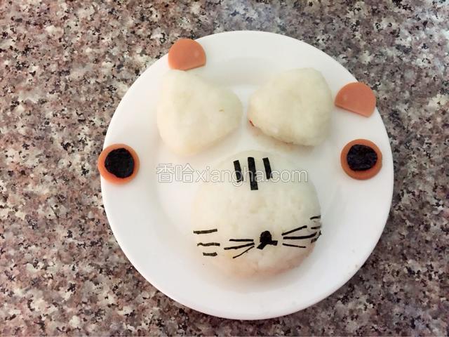 利用保鲜膜做两个三角饭团，火腿肠切片做眼睛跟内耳，海苔剪出眼睛