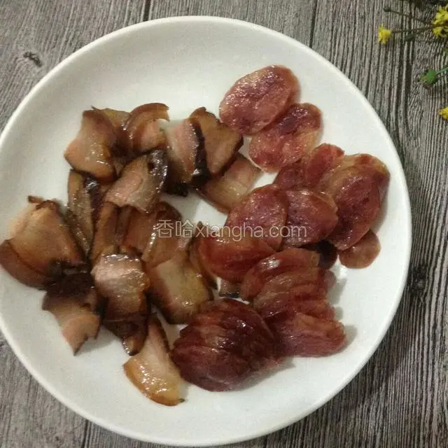 将蒸熟的腊肉和香肠各切片。