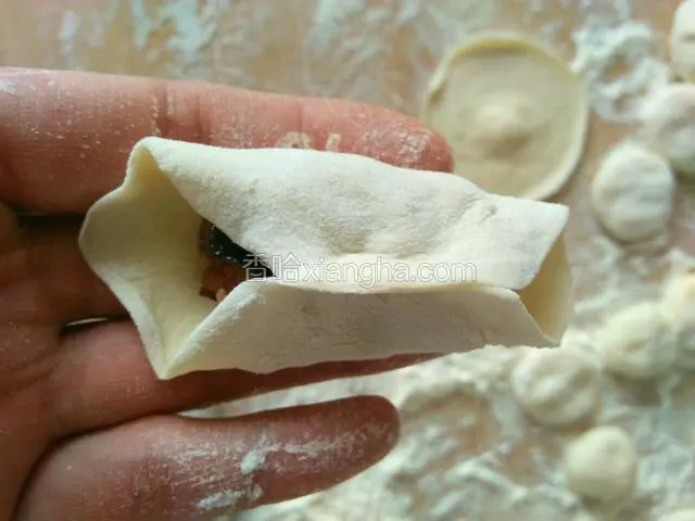 用右手的大拇指和食指将饺子皮的中间捏紧。
