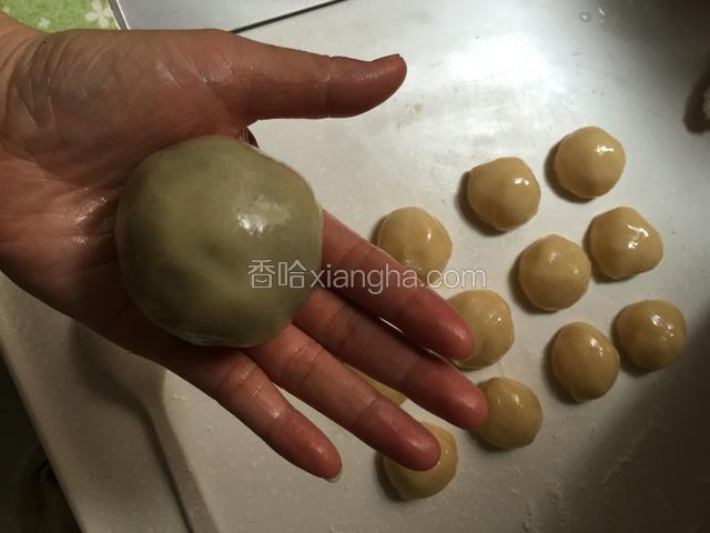 然后把莲蓉和蛋黄一起称，每份70克，一定要蛋黄和莲蓉一起称，因为蛋黄大小不一（这步骤手都是油没拍），然后取一个面皮按扁把馅包住揉圆