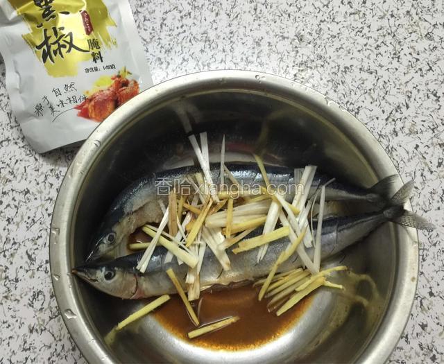 在鱼身上斜切几刀不要切断，放入适量的盐和黑椒调料，一勺料酒和鸡精腌渍一个小时入味，葱姜切段