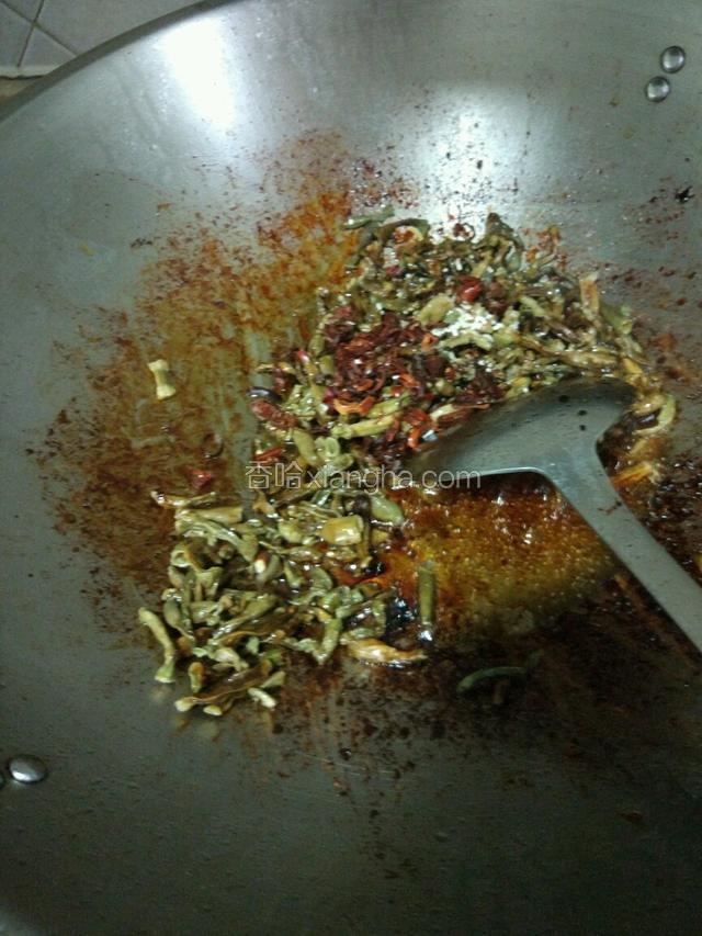 锅里剩下的油，用来炒泡好的干豆角，把大蒜放入，放适量的干辣椒，鸡精，盐，快速翻炒片刻！