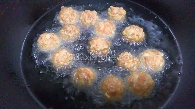 将丸子逐个下入油锅中进行第一次炸，火不要大中火即可