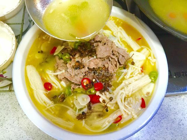 将涮熟的肥牛卷铺在黄豆芽上，用勺子舀入沸腾的汤汁；