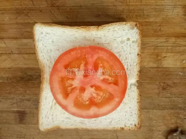 铺好一片土司，上面放两片火腿肠，一片西红柿。