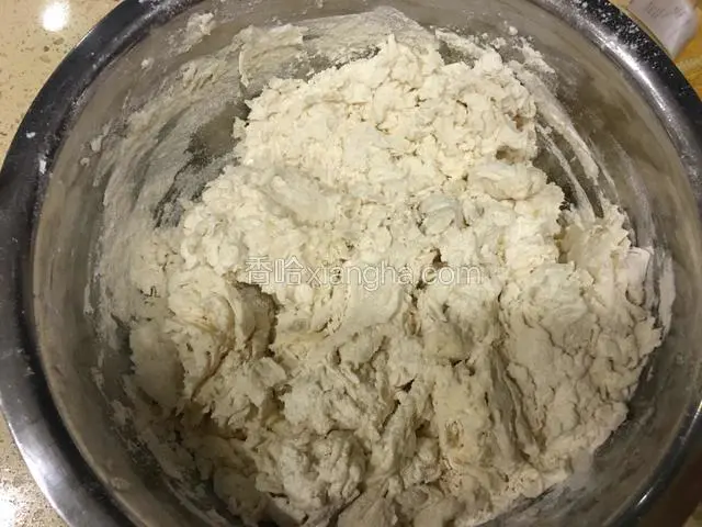 把酵母水缓缓倒入面粉中，把面粉搅拌成絮状。