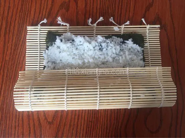从一端卷起，一边卷一边拉动寿司帘并向下按压紧实