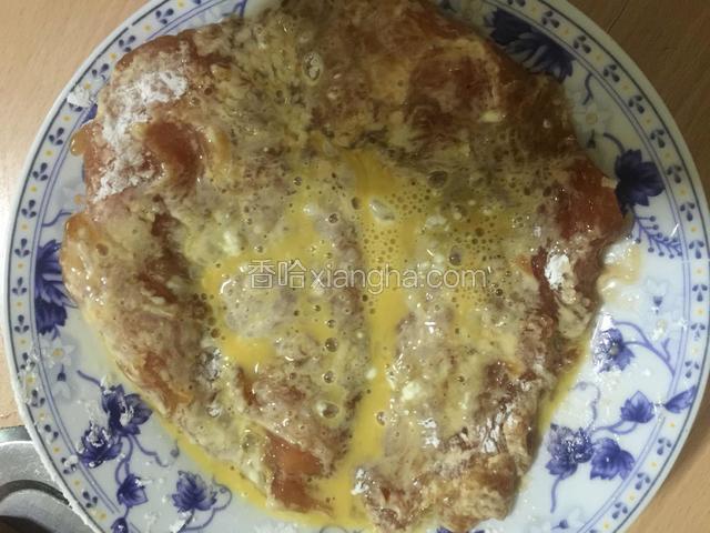 将蘸好淀粉的鸡胸肉放入蛋液中，裹满蛋液。