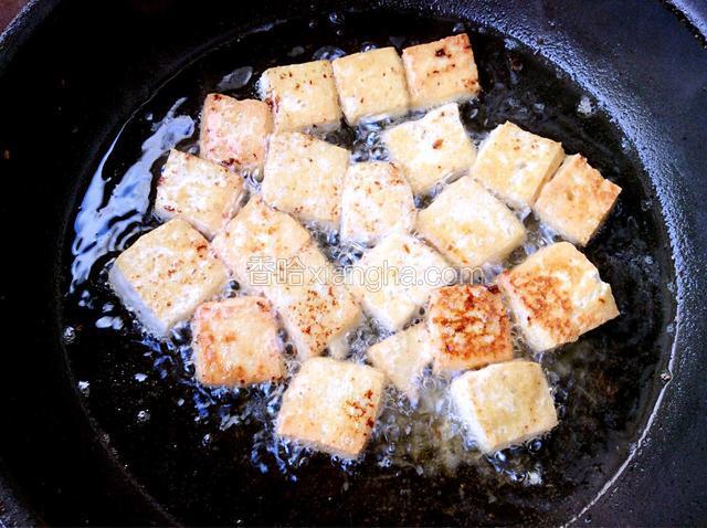 豆腐放入煎鱼的油锅中，煎至两面金黄