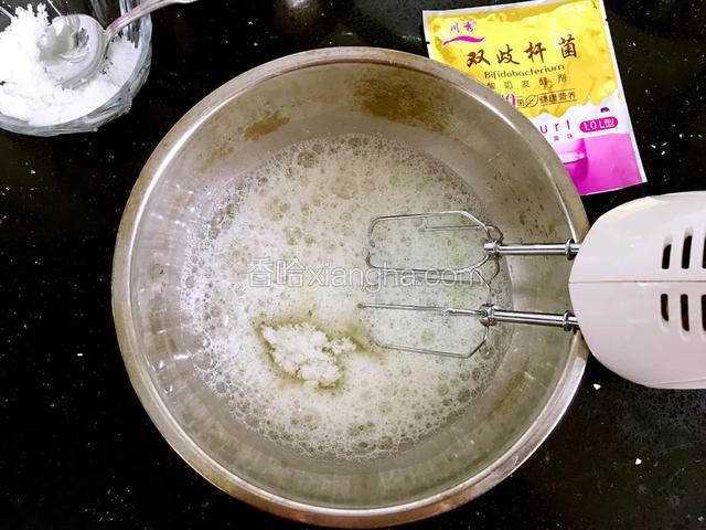 蛋白中滴入5滴柠檬汁。用电动打蛋器打至鱼眼状时，加入20克的糖，继续打发。