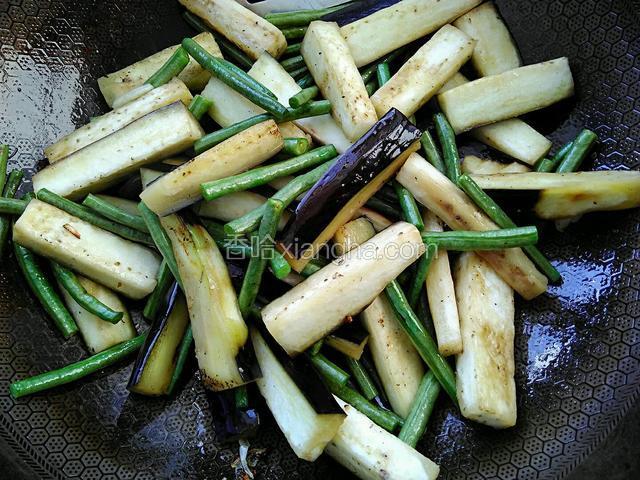 倒入茄子和豆角。翻炒均匀至裹上油花。