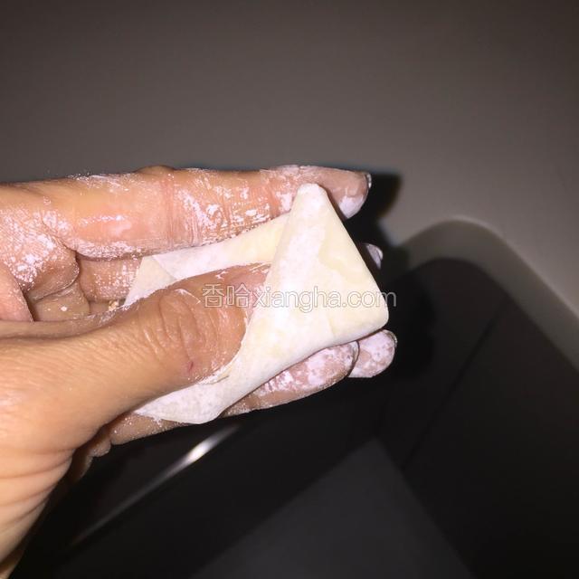 把左手的拇指放在刚在折的角上，把左边的角折过去，如图