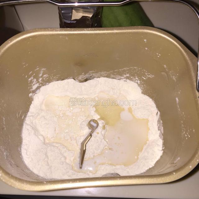 将面粉放入面包桶里，面粉中间挖窝放入酵母，在面粉左边放入盐，右边放入白砂糖，放入牛奶和鸡蛋液，黄油不放，放在室温软化，开启和面程序和面