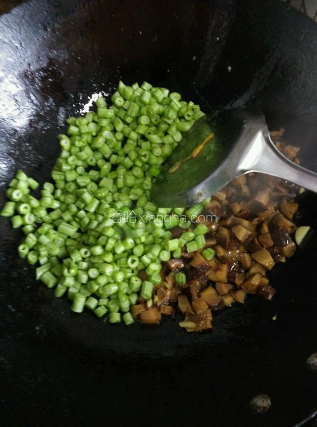 把香菇摆一边，倒入切好的豆角翻炒片刻